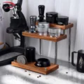 Bestücktes Regal auf Marmor neben einer Hebel-Espressomaschine und einem schwarzen Milchkännchen, verstreute Bohnen