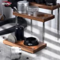 Nähere Ansicht der unteren Ebene mit Dosierbecher, Trichter und zwei Puck Screens, ein silberner Distributor auf der Platte