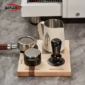 Ahorn-Station mit Siebträger auf dem schwarzen Pad, Distributor, Tamper und weißem Milchkännchen auf der Platte