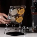 Hand nimmt ein silbernes Sieb aus dem IKAPE Ständer mit sechs Aufnahmen, zwei Aufnahmen bleiben frei