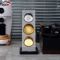IKAPE Siebständer mit drei Aufnahmen, ein silbernes und zwei goldene Siebe, auf der Arbeitsfläche neben einer Mühle