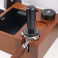 Tamper steht in einem Siebträger auf einer Organizer-Box aus Holz, der Kragen über der Basis mit Gravur