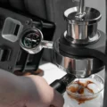 Nahaufnahme von Manometer und Brühgruppe der Alkaid, Espresso tropft in eine Glasschale mit Eis