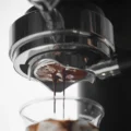 Espresso läuft in zwei Strahlen aus der Unterseite eines bodenlosen Siebs in ein Glas mit Eis