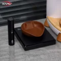 Leere Bohnenschale auf einer schwarzen Waage mit der schwarzen Sprühflasche, unscharf eine Dose mit Holzbeinen