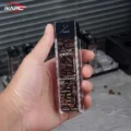 Hand hält ein mit Bohnen gefülltes Röhrchen nah, Röstgrad-Etikett und schwarzer Deckel zur Kamera