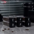 Sechs gefüllte Röhrchen in zwei gestapelten Reihen, die schwarzen Deckel ergeben COFFEE, auf grauer Arbeitsfläche
