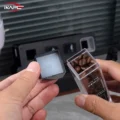 Nahaufnahme eines offenen schwarzen Deckels mit weißer Einlage, neben einem klaren Röhrchen voller Bohnen gehalten
