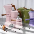 Geöffneter rosa Espressokocher, die obere Kammer liegt auf der Seite und zeigt ihre Filterplatte, der Trichter im Unterteil