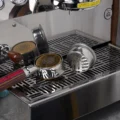 Zwei goldene Clockwork-Siebe in Siebträgern und ein silbernes auf der Seite, auf der Abtropfschale einer Maschine
