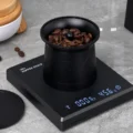 Nähere Ansicht des Bechers voller Bohnen auf der Digitalwaage, die Hebelspitze zwischen den Bohnen
