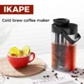 Schwarzer Cold-Brew-Krug auf einem weißen Tisch neben einem roten Becher Eiskaffee mit Limette, darüber ein IKAPE Banner