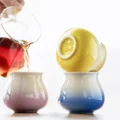 IKAPE Espressotassen bunt aus Keramik: Getränk fließt in eine rosa glasierte Tasse, eine gelbe umgedreht auf einer blauen