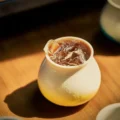 Gelbe Verlaufstasse mit Eiskaffee auf einem Holztisch in warmem Sonnenlicht