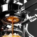 Espresso fällt in einem dünnen Strahl aus der Unterseite des Siebs in ein Glas mit Eis