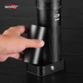 Hand nimmt den Pulverbecher vom Sockel der IKAPE Mühle, darüber Skala und Logo