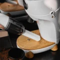 Weißer IKAPE Sauger mit Flachdüse entfernt Kaffeemehl vom Holzsockel einer weißen Mühle