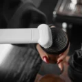 Bürstenaufsatz des weißen IKAPE Saugers reinigt den geriffelten Boden eines Tampers in einer Hand