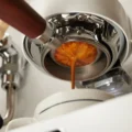 Espresso loopt uit een bottomless portafilter in een wit kopje op een witte espressomachine