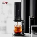 Ständer hält eine tragbare Maschine über einem Glas mit Eis auf einer kleinen Waage, eine Handmühle unscharf