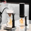 Ständer hält einen Pour-over-Dripper aus Glas unter einer Schwanenhalskanne, daneben ein Ständer mit tragbarer Maschine