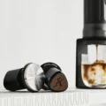 Gerillte Stahlfläche des Tampers neben einem schwarzen Teil mit abgerundet dreieckiger Holzoberseite, Aufdruck Impact Tamper