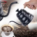 Hand gießt einen dünnen Strahl aus der schwarzen Schwanenhalskanne in einen Handfilter mit Kaffeemehl