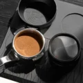 Draufsicht auf einen Siebträger mit geebnetem Kaffeemehl, daneben der Distributor kopfüber mit sichtbarer Basis