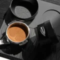 Draufsicht auf ein geebnetes Kaffeebett im Siebträger, rechts liegt der Distributor auf der Seite