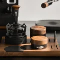 Schwerkraft-Distributor mit Holzkopf auf einem Holztablett neben einem WDT-Tool und einem höheren Werkzeug mit Holzkopf