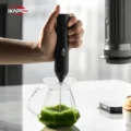 Aufschäumer quirlt ein grünes Getränk in einem Glaskrug, von oben in einer Hand gehalten