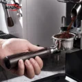 IKAPE Hantom Bottomless-Siebträger unter dem Auswurf einer Mühle, Kaffeemehl fällt ins Sieb