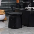 V2 Becher mit aufgesetztem Deckel auf grauer Arbeitsfläche neben einem schwarzen Organizer mit Siebträger