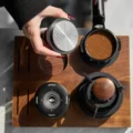 Draufsicht auf den umgedrehten Tamper mit Edelstahlboden mit Ringen, daneben ein Siebträger mit Ringmuster im Puck
