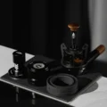 Die drei Werkzeuge des Sets bei gedämpftem Licht auf einem dunklen Tablett, das WDT-Tool auf einem Siebträger mit Kaffeemehl