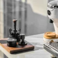 Dreiteiliges Set auf einem Holztablett auf Marmor, daneben eine Mühle und eine Espressomaschine