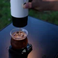 Weiße IKAPE K1 gießt in der Dämmerung Espresso in ein Glas mit Eis auf einer Digitalwaage