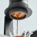 Espresso läuft aus einer tragbaren Maschine im Ständer in eine kleine Glastasse