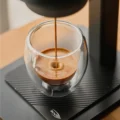 Espresso läuft aus der K2 in ein doppelwandiges Glas auf der gerippten Bodenplatte ihres Ständers