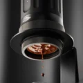 Nahaufnahme von unten: bodenloses Sieb der K2 Pro, Espresso tropft vom Boden, IKAPE Logo am Kragen