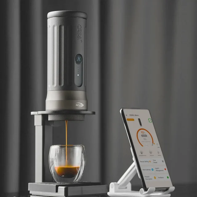 IKAPE Kapo K2 Pro tragbare Espressomaschine im Ständer brüht einen Shot ins Glas, daneben die App auf einem Telefon