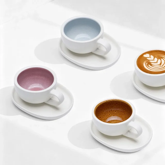 IKAPE Latte Tasse mit Untertasse in drei Farben von oben: innen blau, rosa und braun glasiert, eine Tasse mit Latte Art