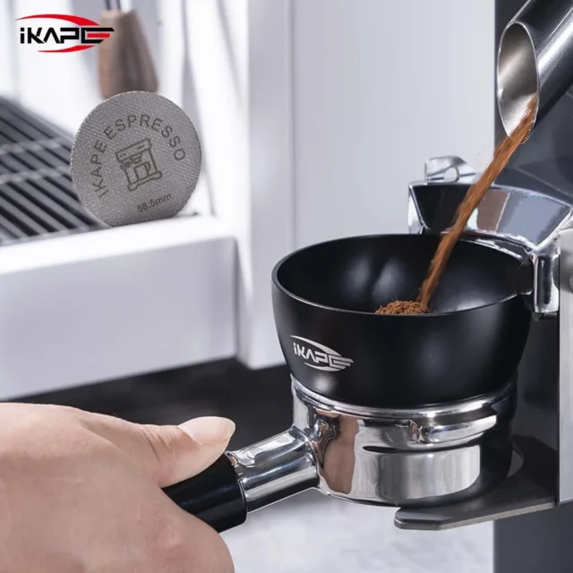Kaffeemehl fällt aus dem Auswurf einer Mühle in den schwarzen Trichter auf einem Siebträger, oben links der Puck Screen