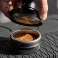Tamper abgehoben, darunter ein getampter Puck mit Ringmuster im Sieb
