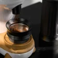 Kaffeemehl fällt aus einer Mühle in den Dosiertrichter auf einem Sieb, auf einem Holzständer