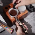 WDT-Tool rührt Kaffeemehl in einem Trichter auf dem Perlweiß Siebträger, der in einer Tamperstation aus Holz liegt