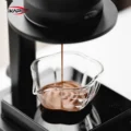 Nahansicht: Espresso läuft in das Petal Glas auf einer schwarzen Waage, die Blattmarkierungen auf dem Glas