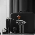 Handmühle mit Holzknauf, zwei Bohnenröhrchen und ein Puck-Bläser vor der geschlossenen IKAPE Tasche