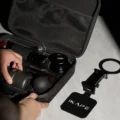 Hände packen eine tragbare Espressomaschine in die offene IKAPE Tasche, daneben der klappbare IKAPE Ständer