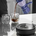 Espressokocher gießt Kaffee in zwei Gläser mit Eis, die schwarze IKAPE Keramikkochplatte im Vordergrund